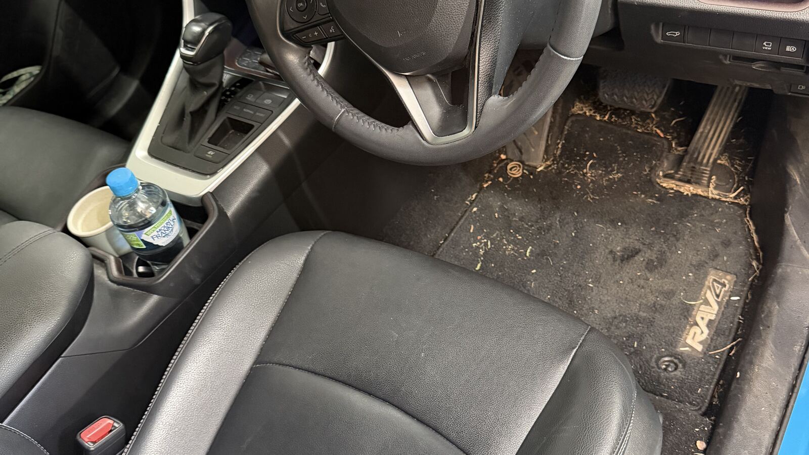 A Toyota RAV4 footwell before detailing, the mat and carpet packed with dried mud